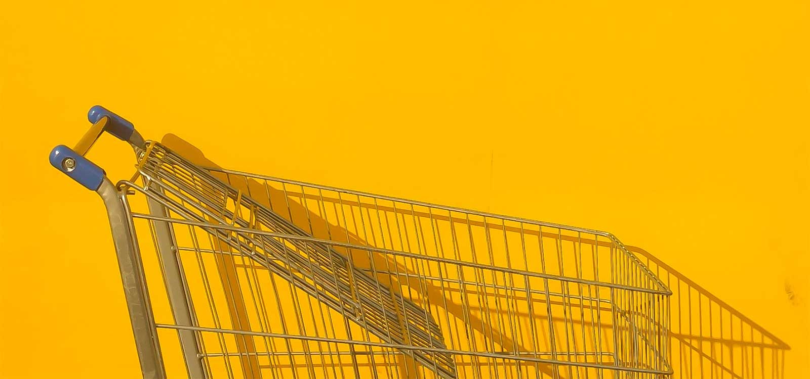 Shopping cart against a yellow wall.